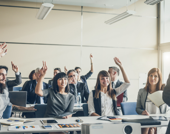 People in a meeting room actively participating in a corporate leadership training session.