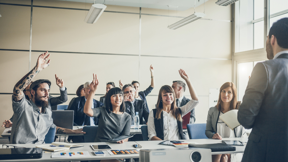 People in a meeting room actively participating in a corporate leadership training session.